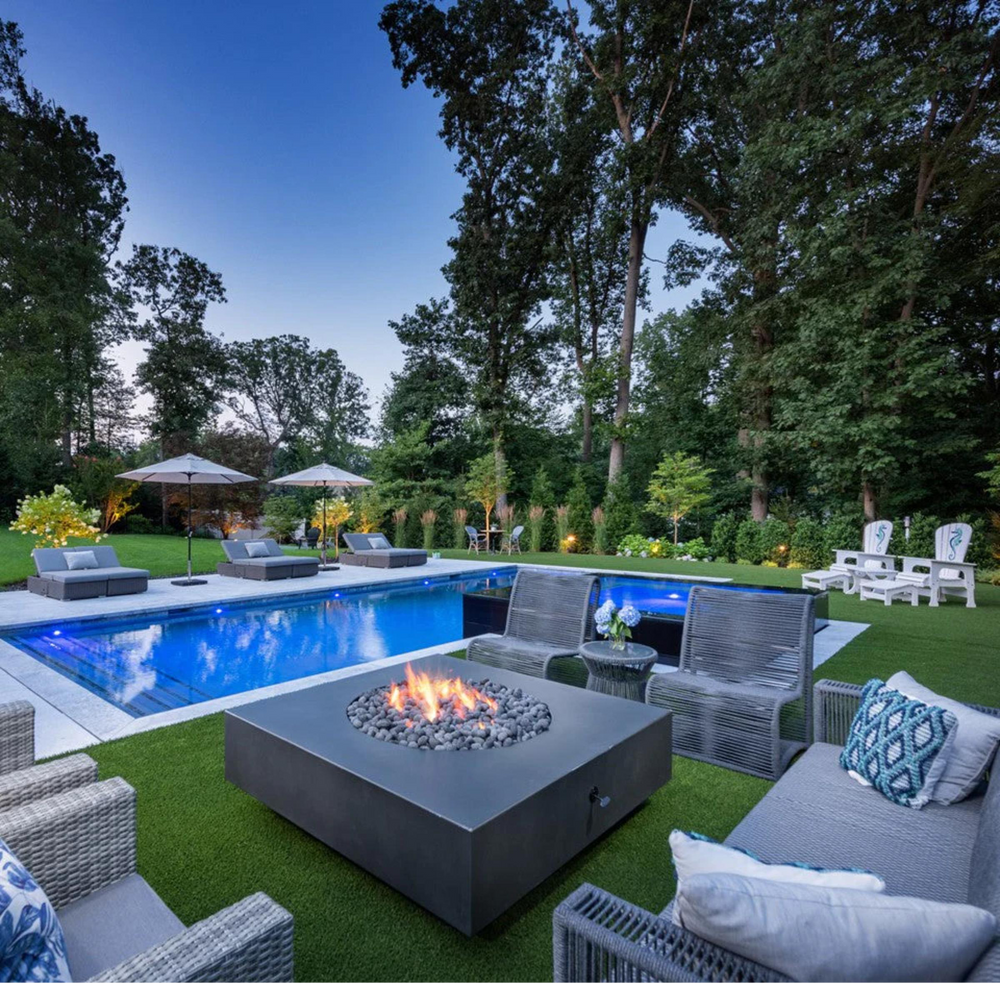 Outdoor patio with pool, fire pit, and seating area surrounded by trees