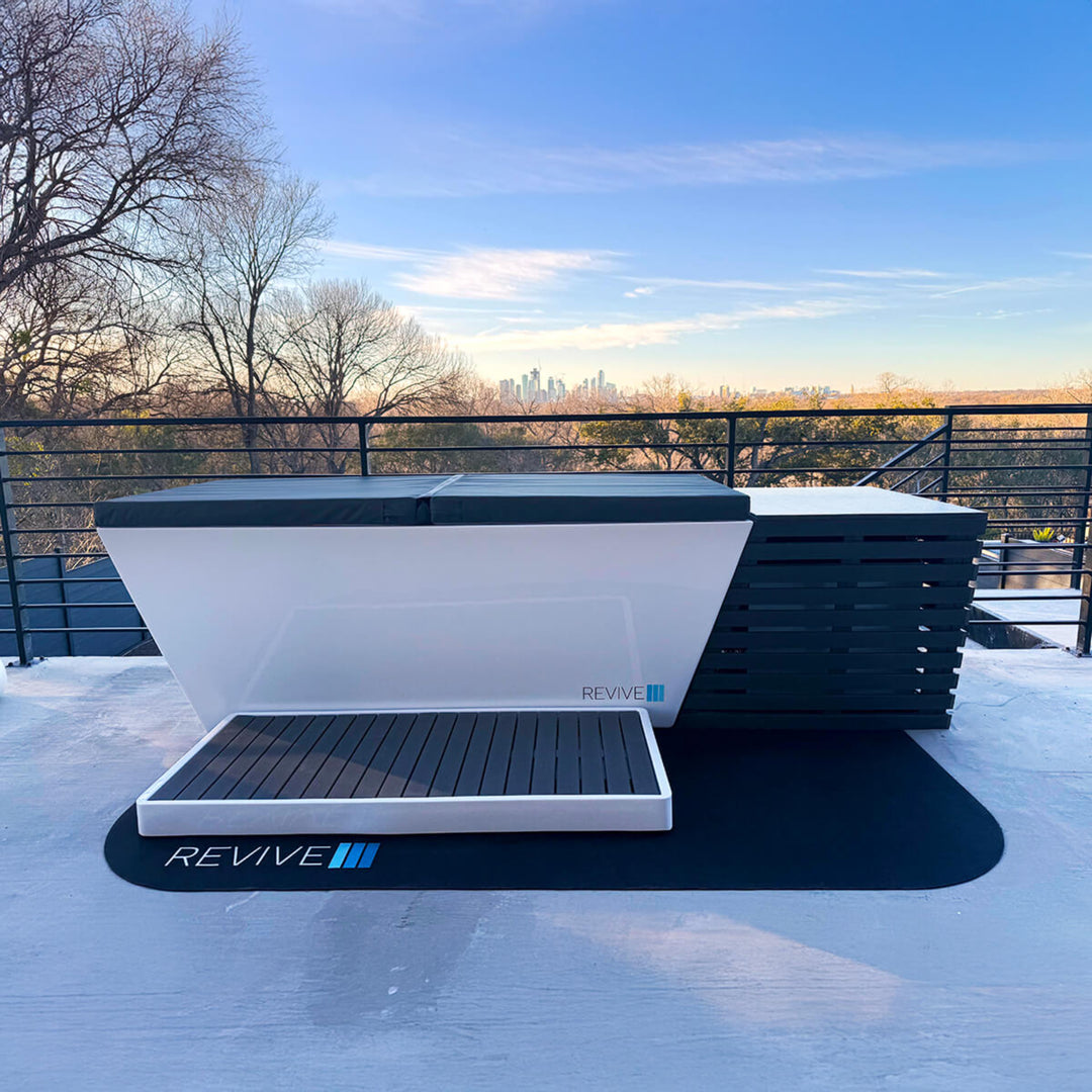 White and black hot tub with 'REVIVE' branding on a rooftop with city skyline in the background