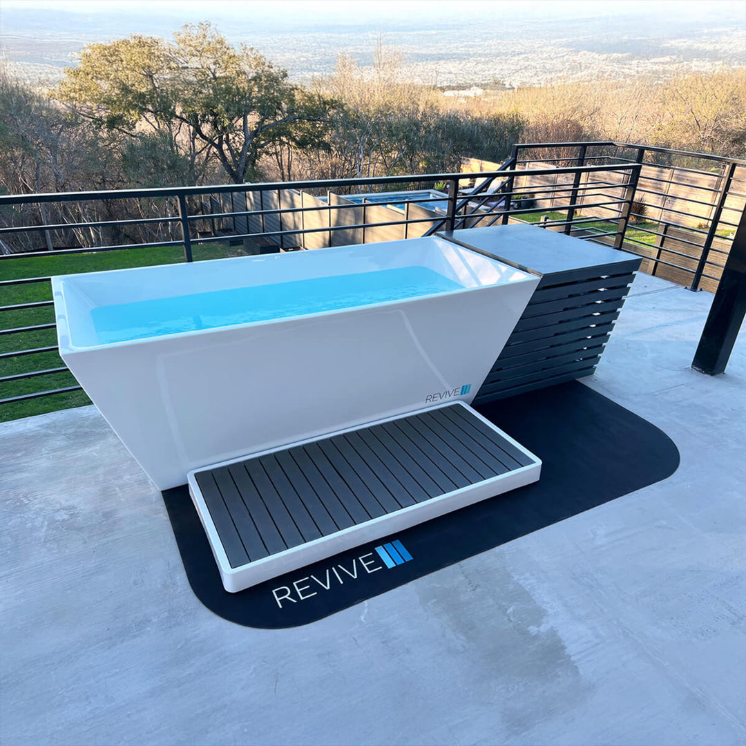 Outdoor cold plunge with 'REVIVE' branding on a patio with scenic background